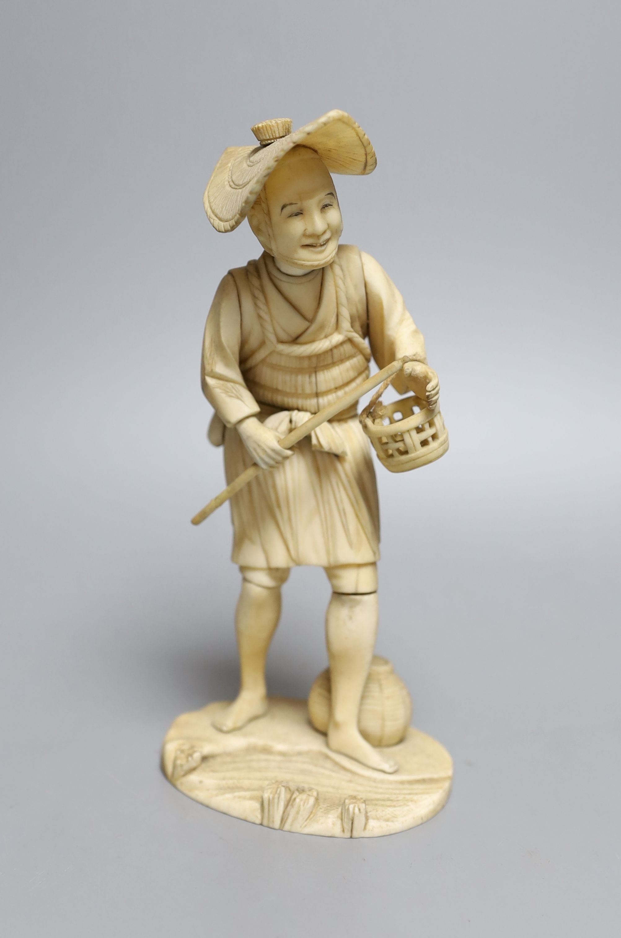 A Japanese sectional ivory okimono figure of a man with a basket, signed inset tablet to base - 19cm tall